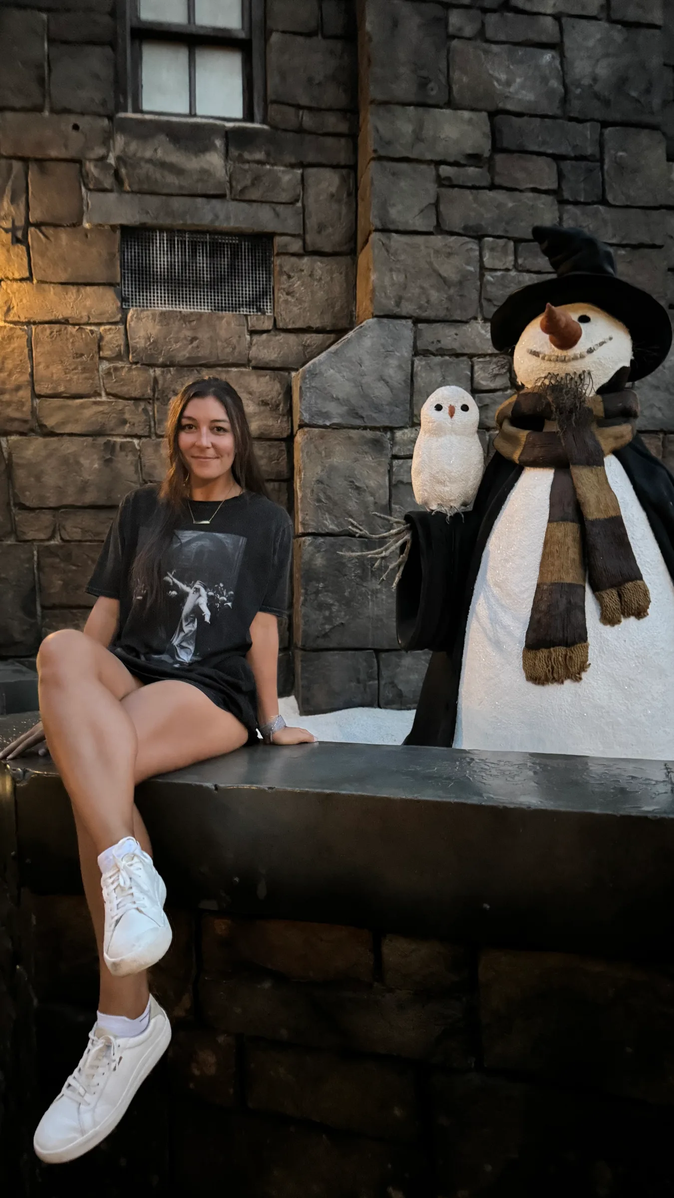 dana sitting next to a snowman in hogsmeade
