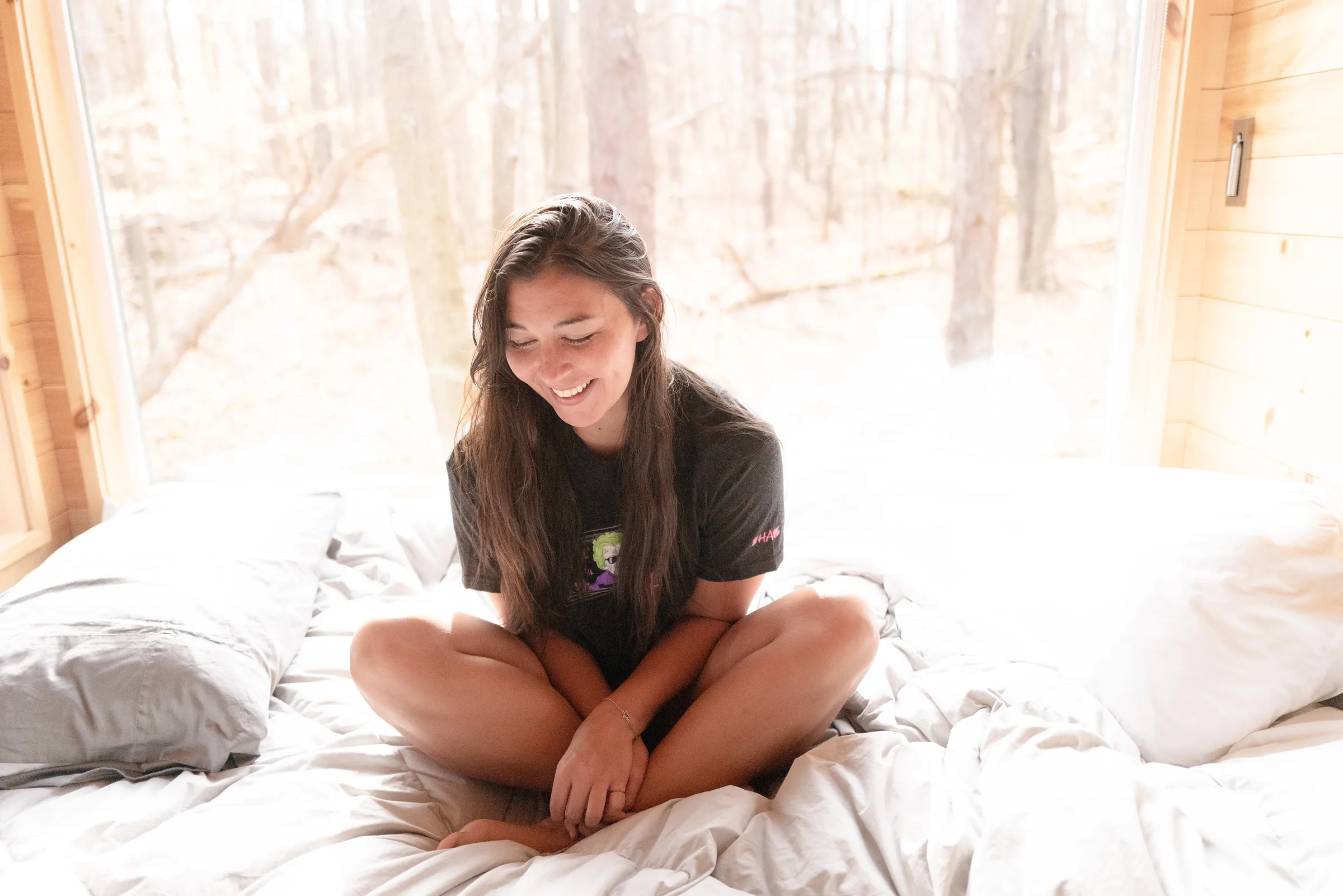 dana sitting on a bed in a Postcard Cabin